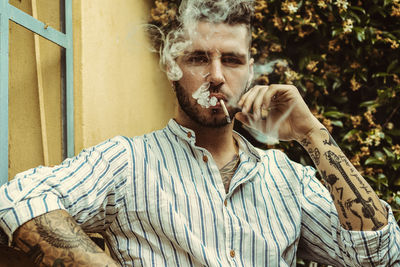 Portrait of young man smoking cigarette outdoors