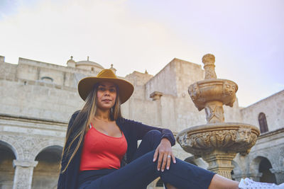 Low angle view of young woman standing against sky