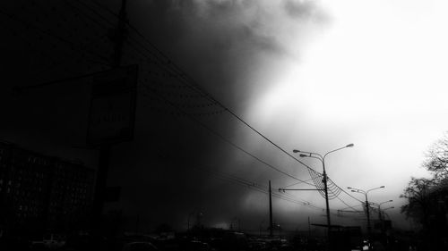 Low angle view of electricity pylon against cloudy sky