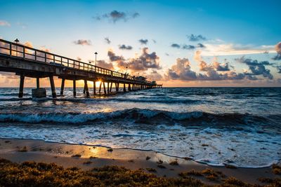 Pier over sea against sky during sunset