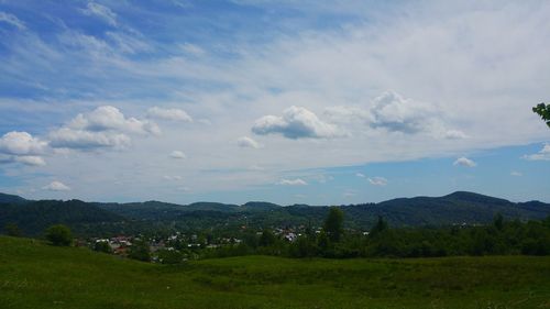 Scenic view of grassy field against cloudy sky