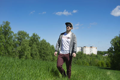 Young man standing on field against sky