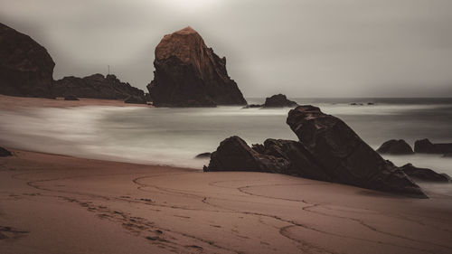 Rock formation on beach against sky