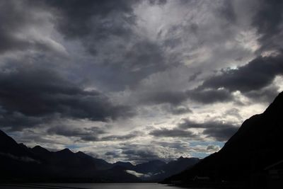 Scenic view of silhouette mountains against storm clouds