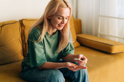 Young woman using mobile phone while sitting on sofa at home