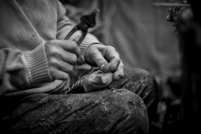 Midsection of man holding pliers while sitting outdoors