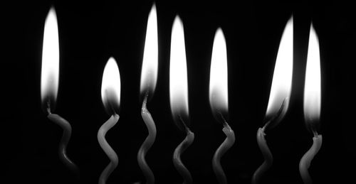 Close-up of illuminated candles against black background