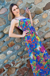 Portrait of smiling young woman standing against stone wall