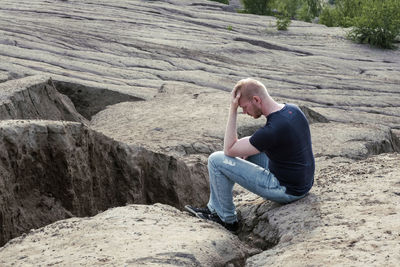 Side view of woman sitting on rock