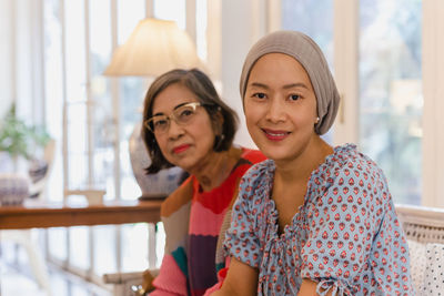 Portrait of asian senior motherand daughter sitting together on sofa at home