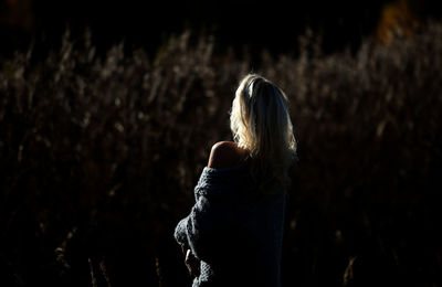 Rear view of mature woman standing outdoors at night