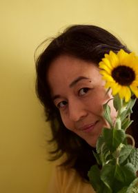 Portrait of smiling young woman against yellow wall