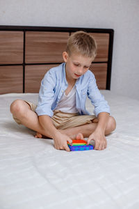Boy playing with toy sitting on bed at home
