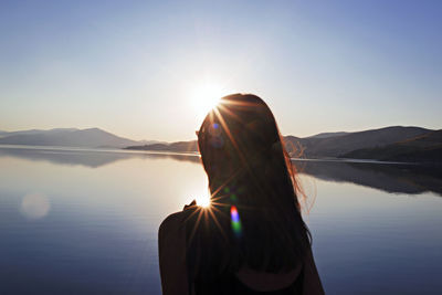Rear view of woman at lake against sky