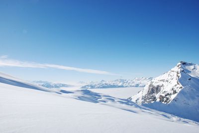 Scenic view of snowcapped mountains against blue sky