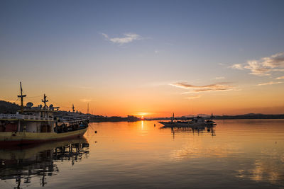 Boats moored at harbor during sunset