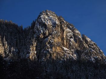 Low angle view of snowcapped mountain against clear blue sky