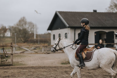 View of girl horseback riding