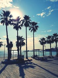 Silhouette palm trees by swimming pool against sky