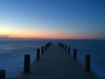 Wooden pier in sea against clear sky