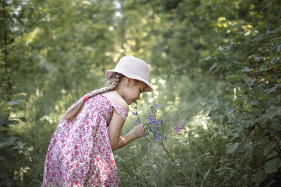 Side view of girl wearing hat standing against plants