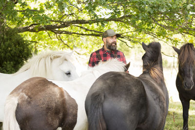 Male farmer standing among horses