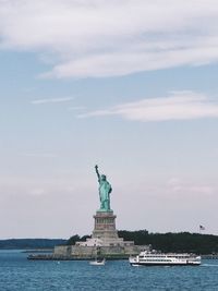 Statue in sea against cloudy sky