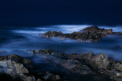 Scenic view of sea and rocks against sky night