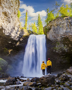 Rear view of woman standing against waterfall