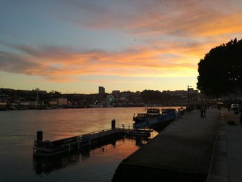 Scenic view of river by buildings against sky during sunset