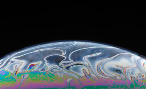 Close-up of multi colored water against black background