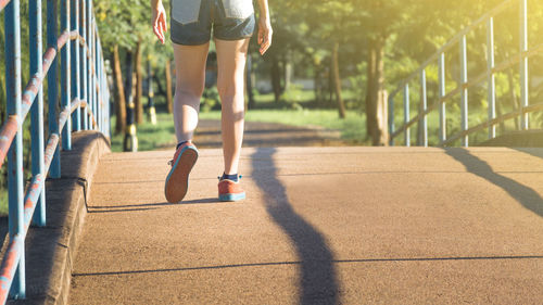 Low section of woman walking on footbridge