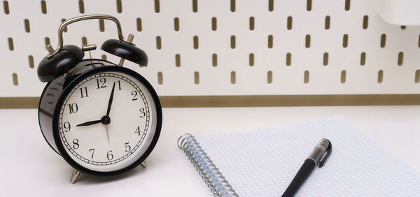 Alarmclock, pen and a notebook placed on white background