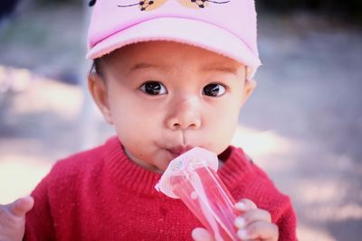 Portrait of cute baby girl having drink while standing outdoors