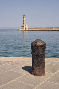 Lighthouse by sea against clear sky