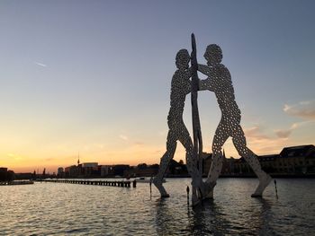 Silhouette of bridge over river during sunset