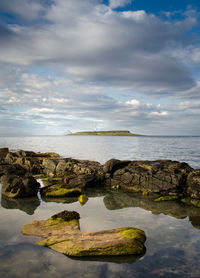 Scenic view of rocks by sea against sky