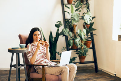 Young woman using phone while sitting on table