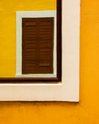 Close-up of closed window of yellow house