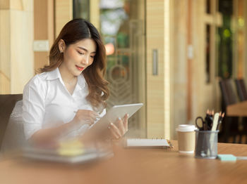 Young woman using mobile phone at table