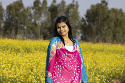 Portrait of smiling young woman standing on field