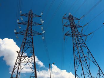 Low angle view of electricity pylon against blue sky