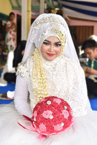 Portrait of smiling bride sitting at home