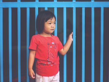 Full length of cute girl standing against blue wall