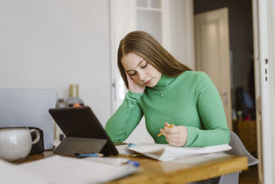 Bored young woman studying at table