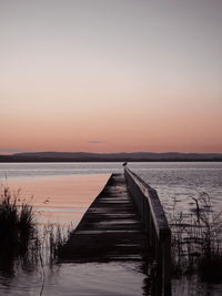 Pier over sea against sky during sunset