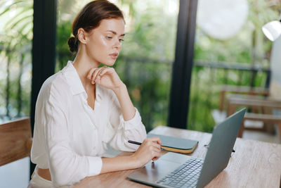 Young woman using laptop while sitting at home