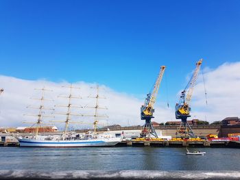 Cranes at commercial dock against blue sky