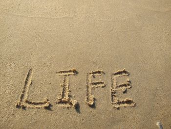 High angle view of text on sand