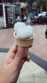 Cropped image of hand holding ice cream cone in city